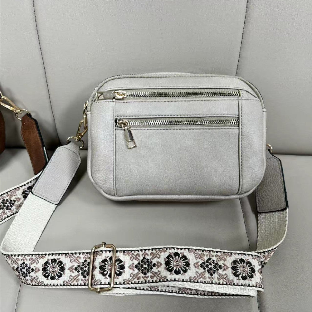 Women’s triple-zip colorblock crossbody bag with embroidered strap.